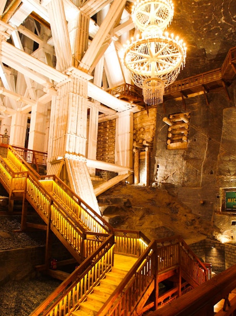 Wieliczka Salt Mine interior with illuminated wooden stairs and chandelier.