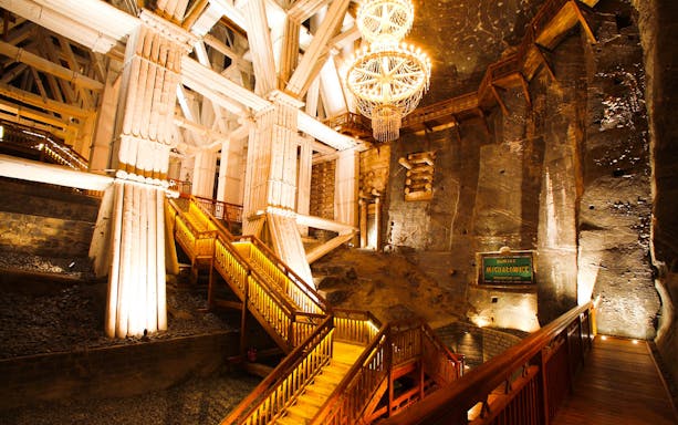 Wieliczka Salt Mine interior with illuminated wooden stairs and chandelier.