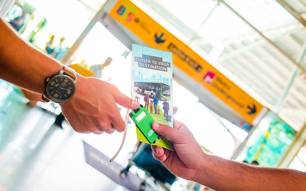 Hand exchanging Aerobus Lisbon Airport Shuttle ticket at terminal.