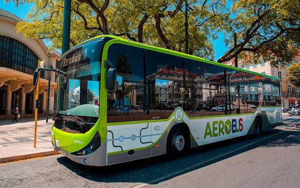 Aerobus shuttle parked at Lisbon street near historic building.