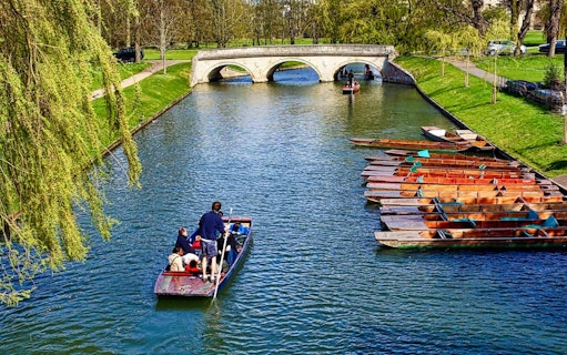 Punting on the River Cam near a stone bridge in Cambridge, England.