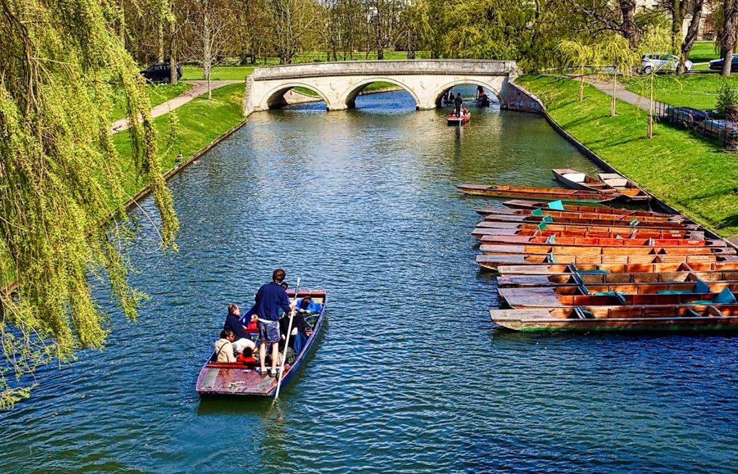 Punting on the River Cam near a stone bridge in Cambridge, England.