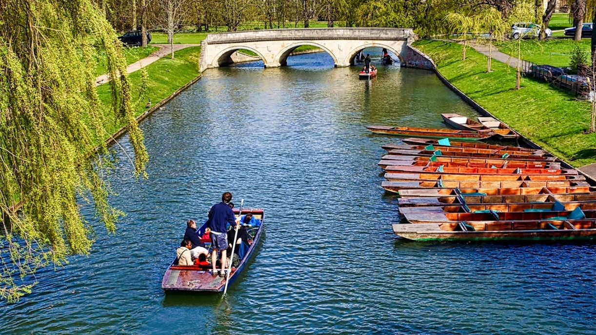 Punting on the River Cam near a stone bridge in Cambridge, England.