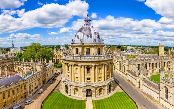 Radcliffe Camera at Oxford University, England, surrounded by historic buildings and green lawns.