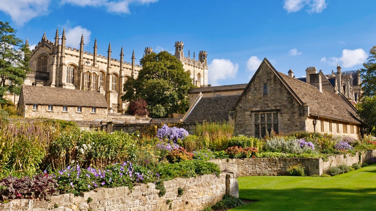 Historic Oxford University building with gardens in foreground.