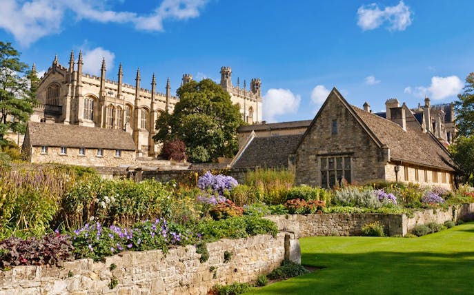 Historic Oxford University building with gardens in foreground.