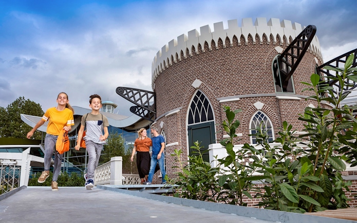 Children running near a brick building at Madurodam Miniature Park.