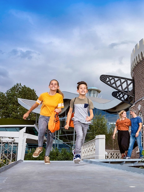 Children running near a brick building at Madurodam Miniature Park.
