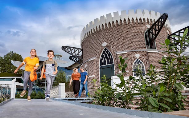 Children running near a brick building at Madurodam Miniature Park.