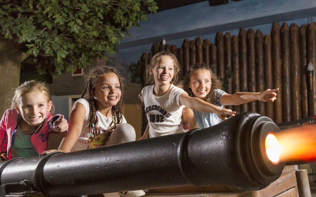 Children interacting with a cannon exhibit at Madurodam Miniature Park.