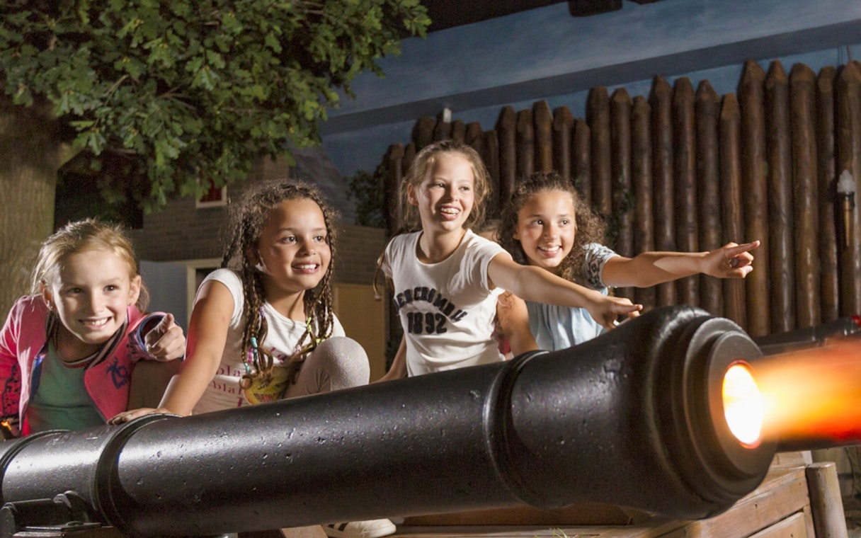 Children interacting with a cannon exhibit at Madurodam Miniature Park.