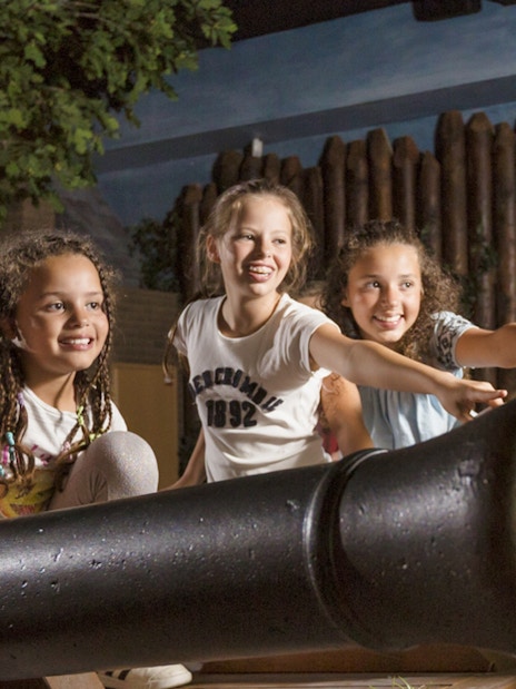 Children interacting with a cannon exhibit at Madurodam Miniature Park.