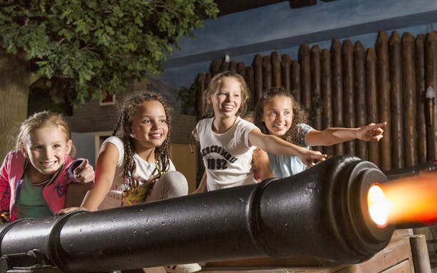 Children interacting with a cannon exhibit at Madurodam Miniature Park.
