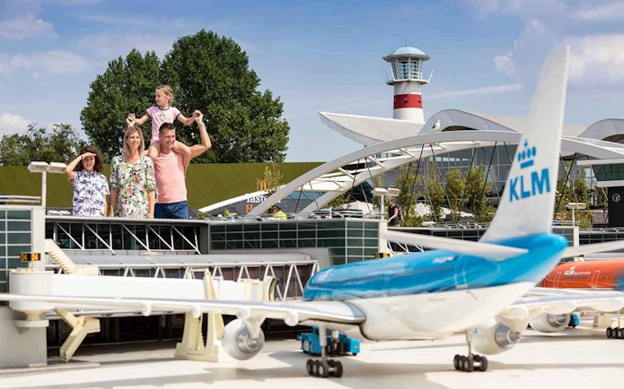 Family exploring Madurodam Miniature Park with KLM airplane model in foreground.