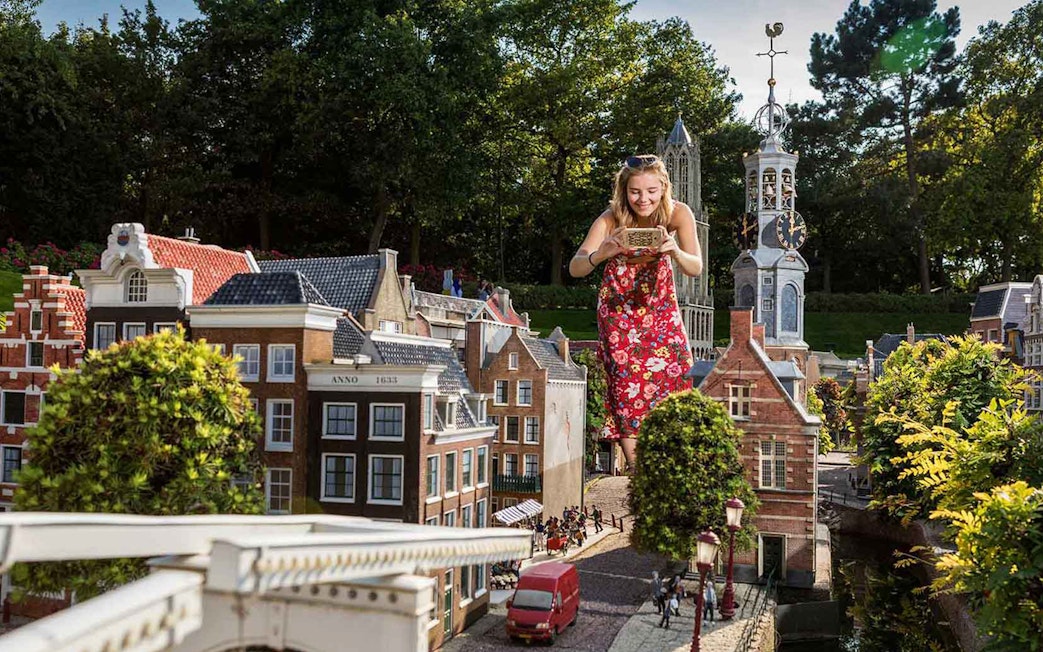 Woman exploring miniature Dutch buildings at Madurodam Miniature Park.