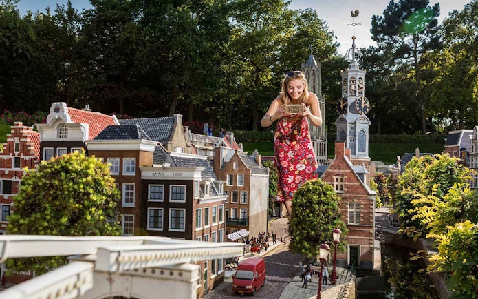 Woman exploring miniature Dutch buildings at Madurodam Miniature Park.