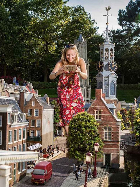Woman exploring miniature Dutch buildings at Madurodam Miniature Park.