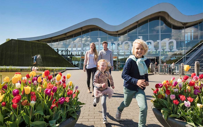 Family enjoying a day at Madurodam Miniature Park with tulips in the foreground.