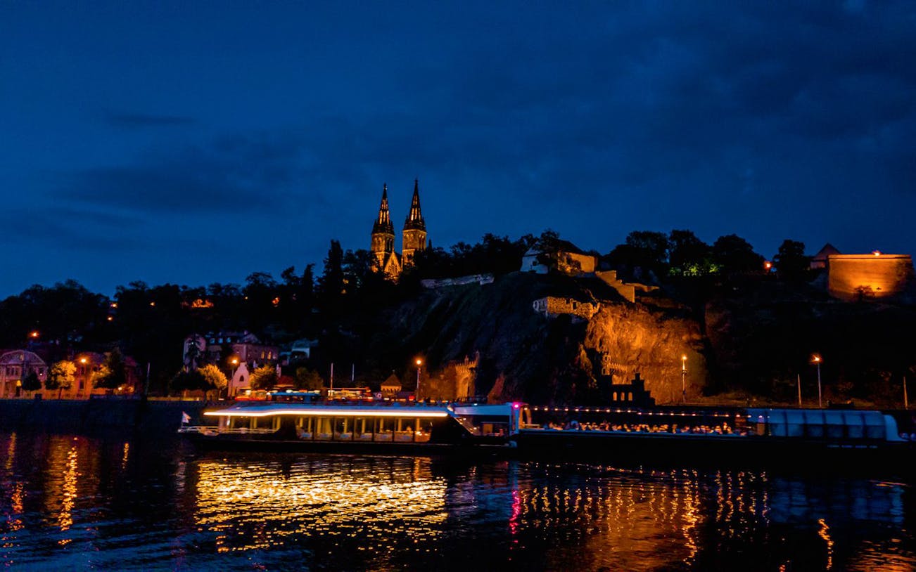 Vltava River cruise at night with illuminated Prague skyline.