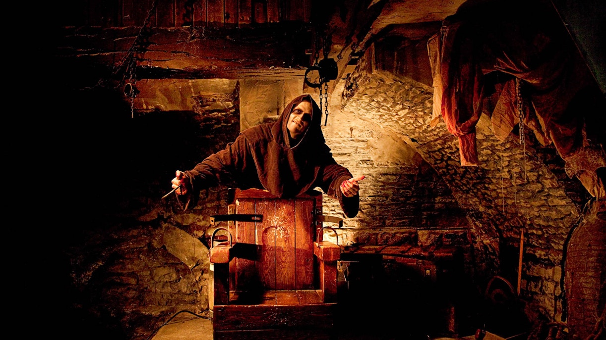 Actor in medieval costume at Amsterdam Dungeon attraction.