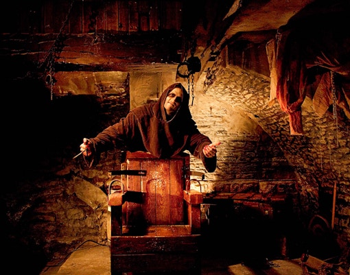 Actor in medieval costume at Amsterdam Dungeon attraction.