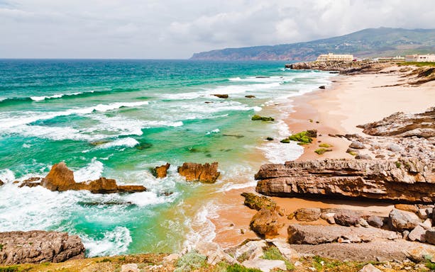 Coastal view of Cabo da Roca with rocky cliffs and turquoise waves near Lisbon.
