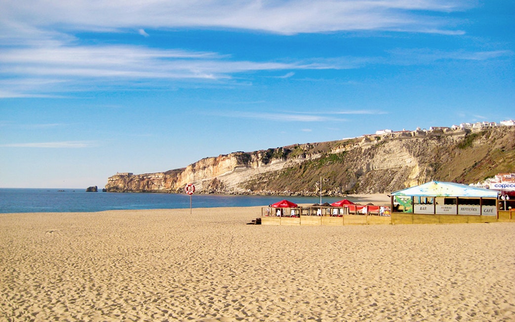 Nazaré beach with cliffs and seaside café, part of Fátima, Óbidos, Batalha & Nazaré day tour from Lisbon.