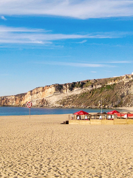 Nazaré beach with cliffs and seaside café, part of Fátima, Óbidos, Batalha & Nazaré day tour from Lisbon.
