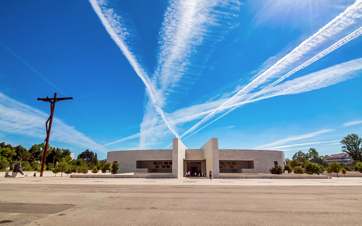 Fátima Sanctuary with modern architecture and cross under blue sky, Portugal.