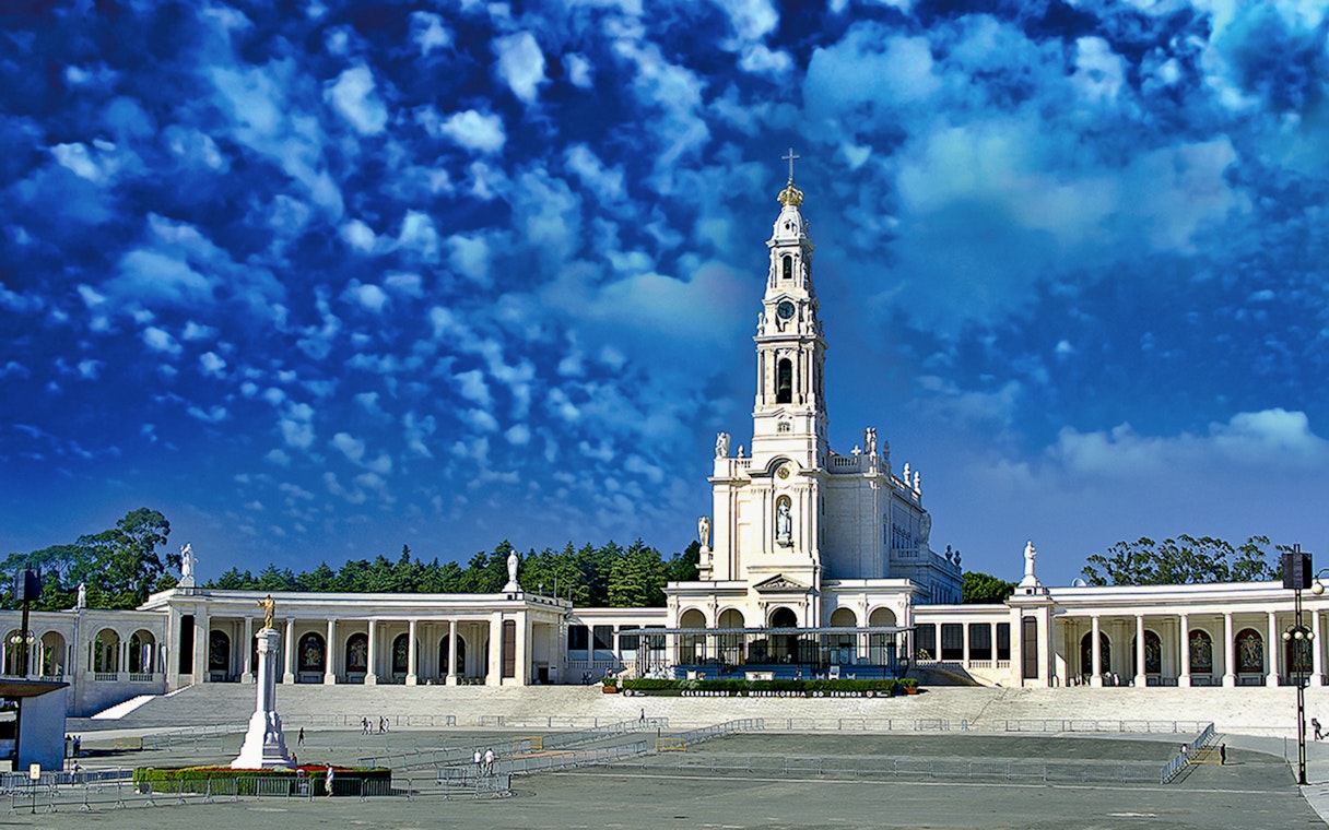 Fátima Sanctuary with basilica tower under a blue sky, seen on a half-day tour from Lisbon.