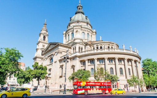 Red double-decker bus in front of St. Stephen's Basilica, Budapest.