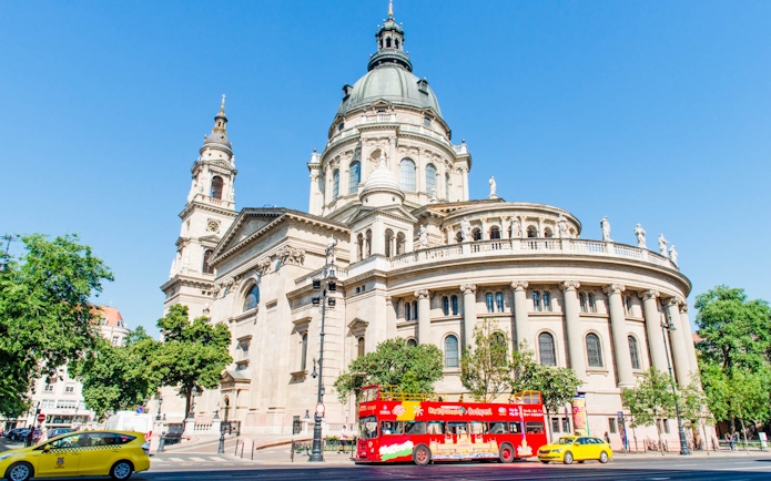 Red double-decker bus in front of St. Stephen's Basilica, Budapest.