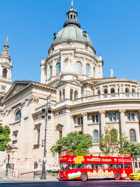 Red double-decker bus in front of St. Stephen's Basilica, Budapest.