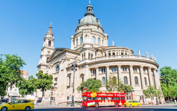 Red double-decker bus in front of St. Stephen's Basilica, Budapest.