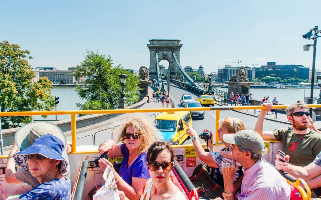 Open-top bus tour crossing Széchenyi Chain Bridge in Budapest.