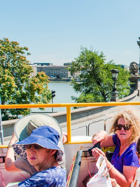 Open-top bus tour crossing Széchenyi Chain Bridge in Budapest.