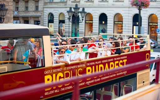 Open-top bus with tourists on a Hop-On Hop-Off tour in Budapest.
