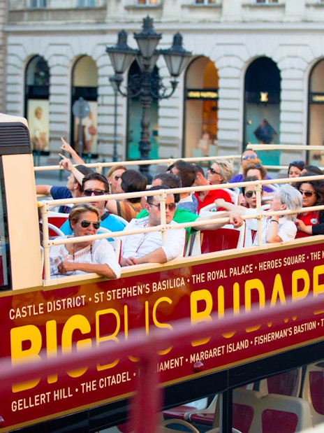 Open-top bus with tourists on a Hop-On Hop-Off tour in Budapest.