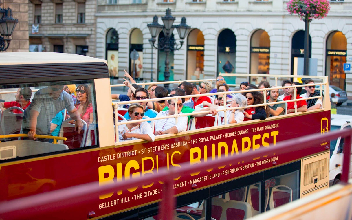 Open-top bus with tourists on a Hop-On Hop-Off tour in Budapest city center.