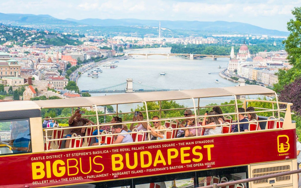 Open-top bus tour in Budapest with view of the Danube River and city landmarks.