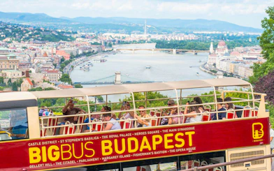Open-top bus tour in Budapest with view of the Danube River and city landmarks.