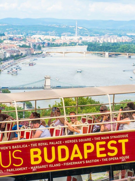 Open-top bus tour in Budapest with view of the Danube River and city landmarks.
