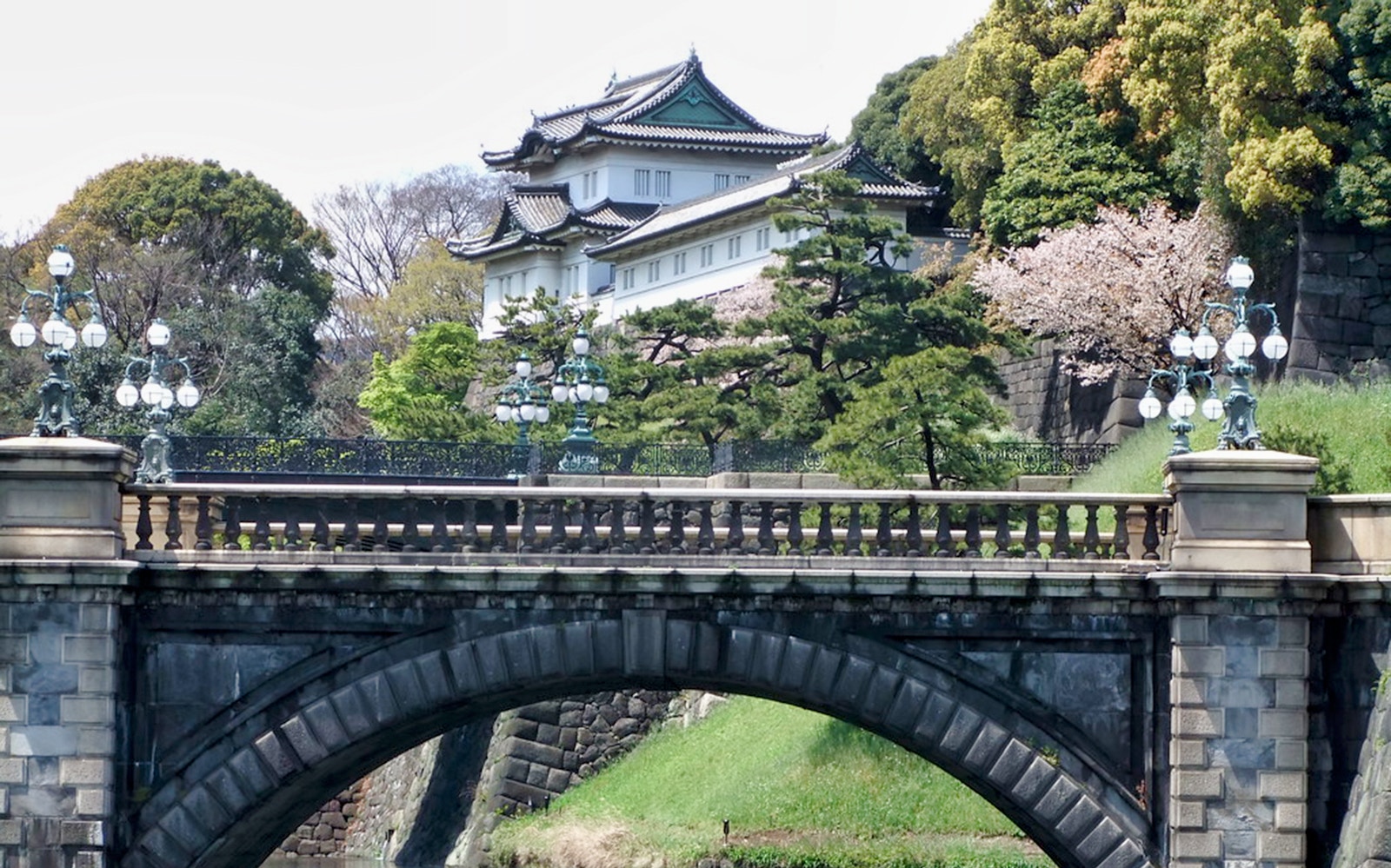 Tokyo Imperial Palace with Nijubashi Bridge in foreground, surrounded by lush greenery.