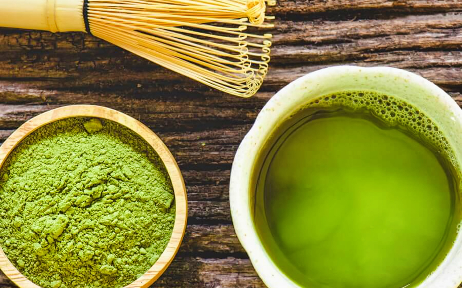 Matcha tea and whisk with green tea powder on wooden table, part of Flavors of Japan Tour.
