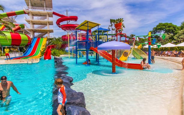 Colorful water slides and play area at Splash Waterpark with families enjoying the pool.