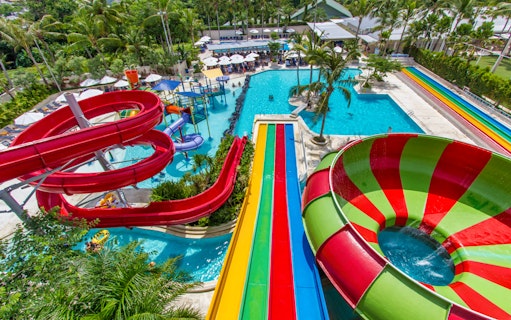 Colorful water slides and pools at Splash Waterpark surrounded by palm trees.