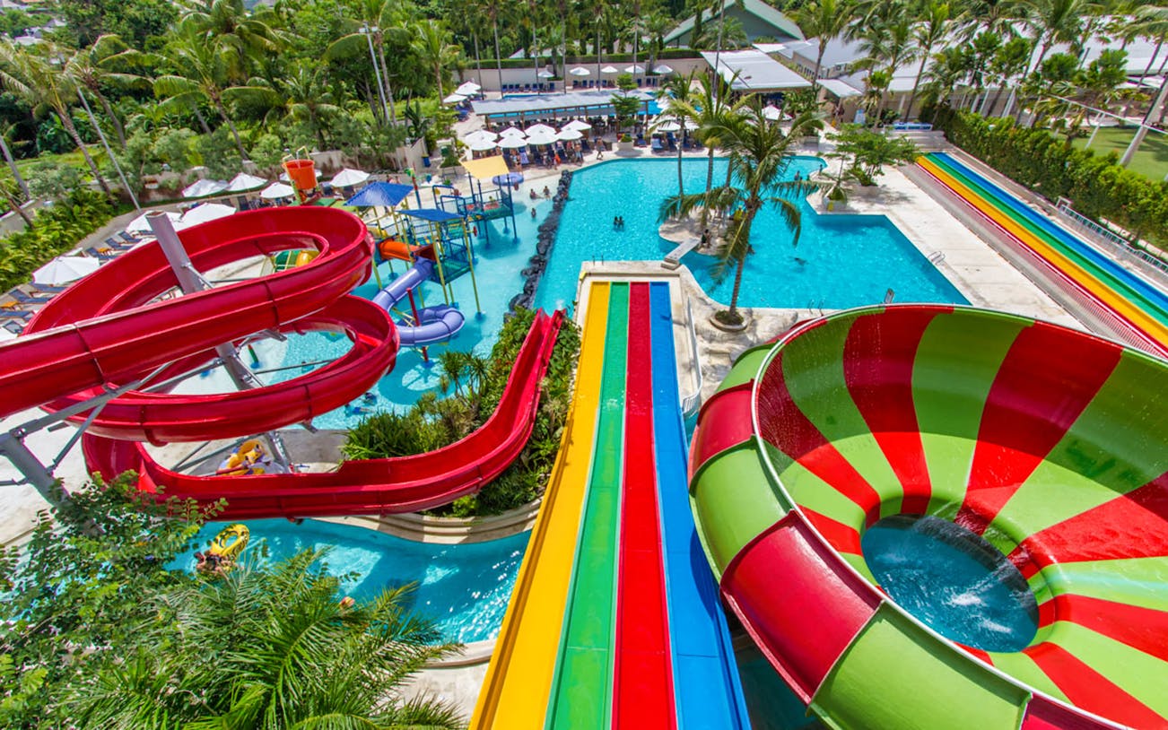 Colorful water slides and pools at Splash Waterpark surrounded by palm trees.