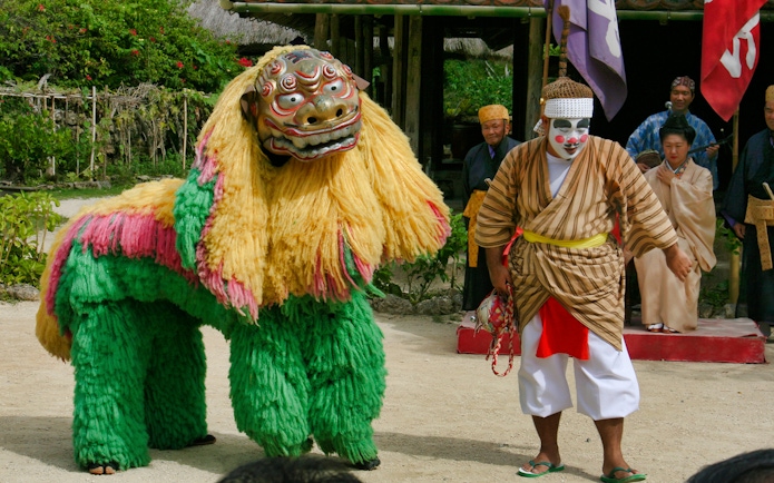 Traditional performance with lion dance and performers at Okinawa Ryukyu Mura Village.