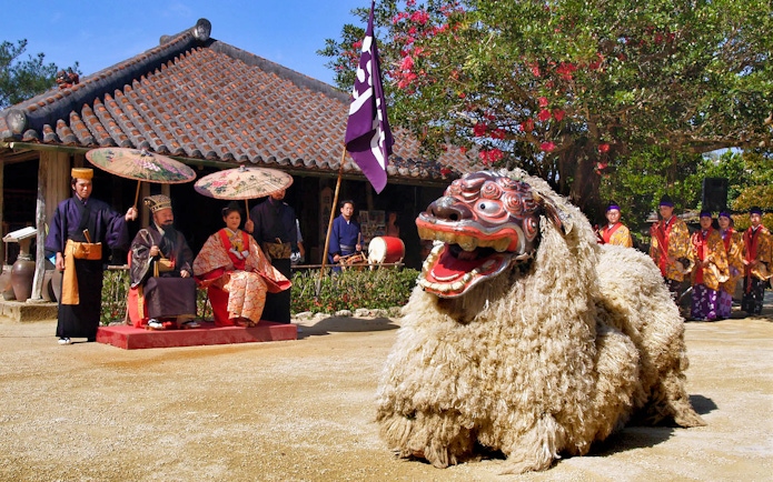 Traditional Ryukyu dance performance at Okinawa Ryukyu Mura Village with performers in cultural attire.