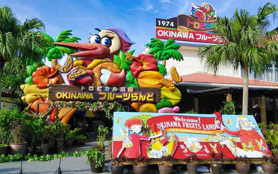 Entrance to Okinawa Fruits Land with colorful tropical fruit decorations and welcome sign.